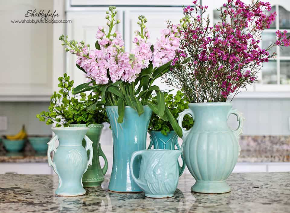 Adding pops of color to a room - these pink and green flowers in teal vases add color to a white kitchen