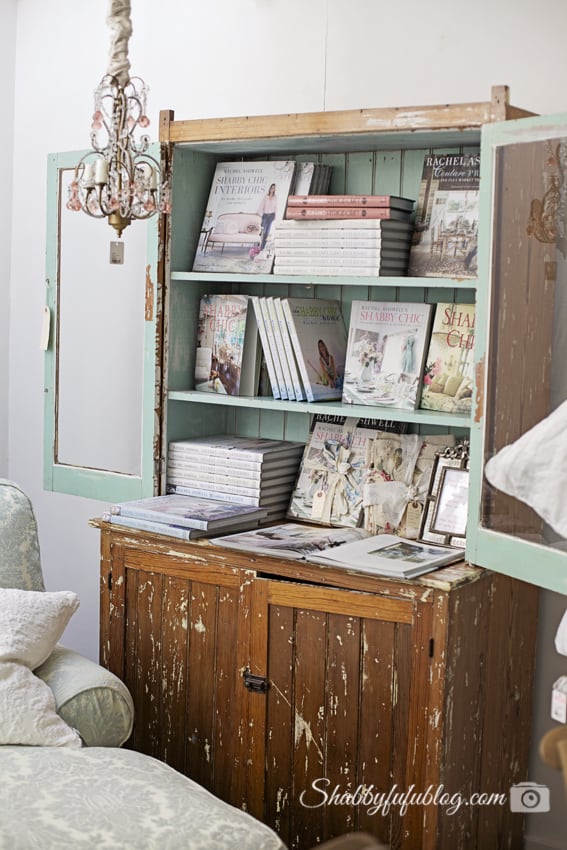 Rachel Ashwell's shabby chic style book collection, displayed in a beautiful distressed wooden china cabinet painted a stunning mint green.