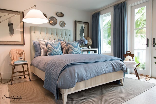 Master bedroom in the HGTV Dream Home 2016 - a bedroom accented with blue; a large upholstered headboard and french doors that lead to the pool.