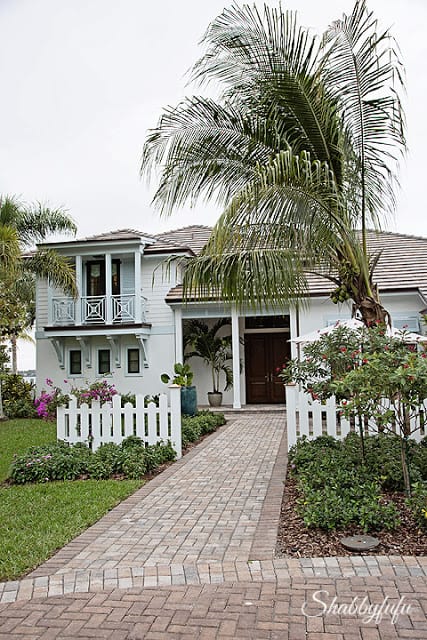 The front of the HGTV Dream Home 2016. A white picket fence, palm trees, and beautiful brick walkway.