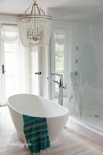 Master bathroom in the HGTV Dream Home 2016 - this bathroom is elegant with white and teal touches and a crystal chandelier.