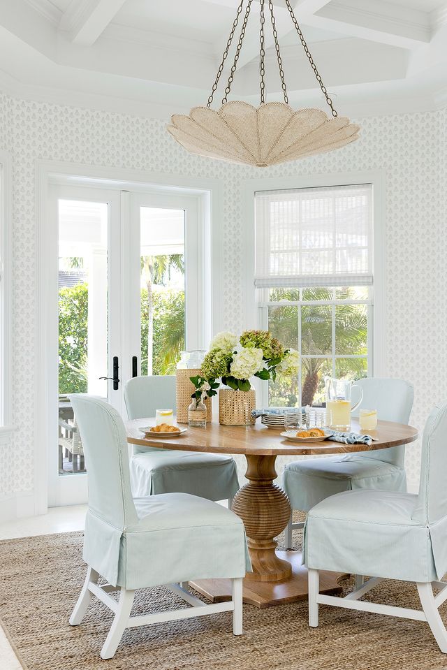 Dining space idea featuring white living room with round table and light blue chairs in a costal elegant style