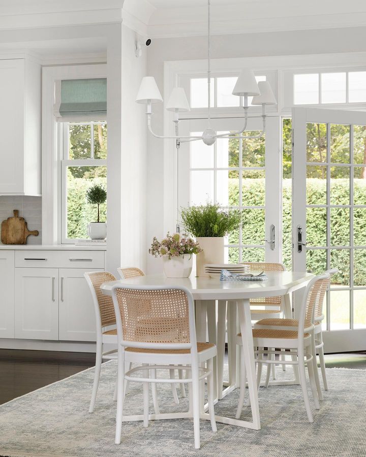 Dining space idea featuring dining space next to a kitchen with small table and white bamboo chairs in a costal elegant style