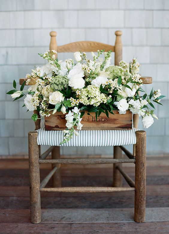 floral arrangement in a wooden crate on top of a chair