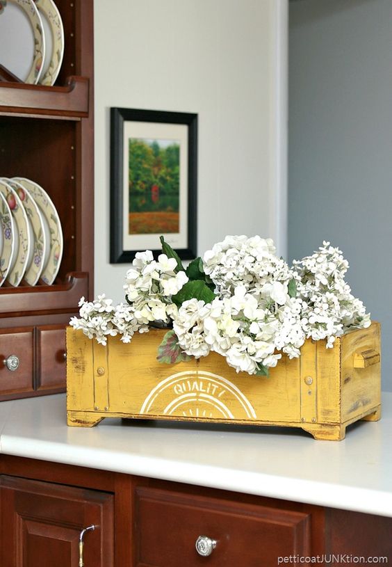yellow wooden crate with a floral arrangement in it