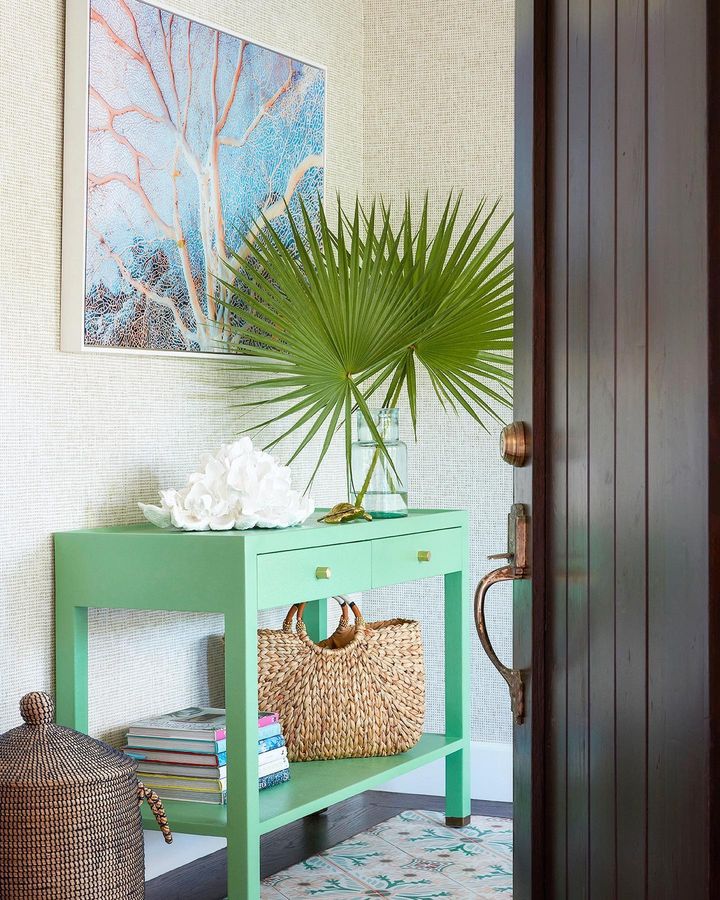 palm tree home decor idea featuring a green console table with a large vase with two palm tree leaves