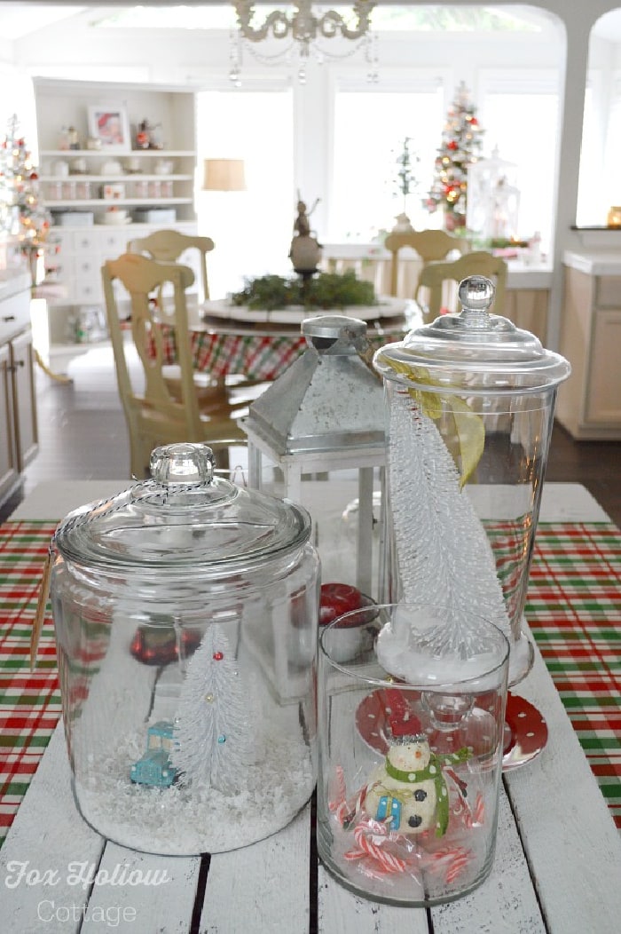 Glass cannisters with Christmas decor inside and dining area in the background