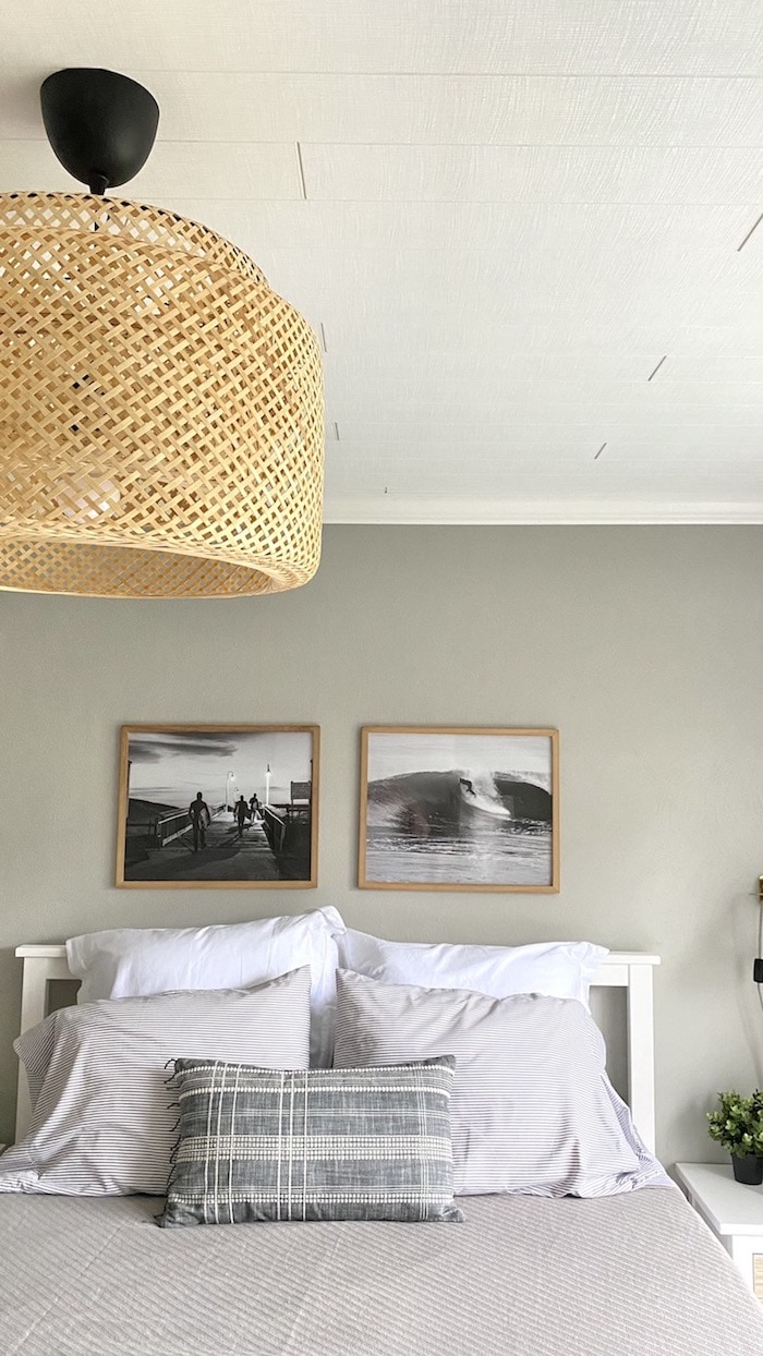 bedroom image showing rattan light fixture, gray bedding and black and white artwork