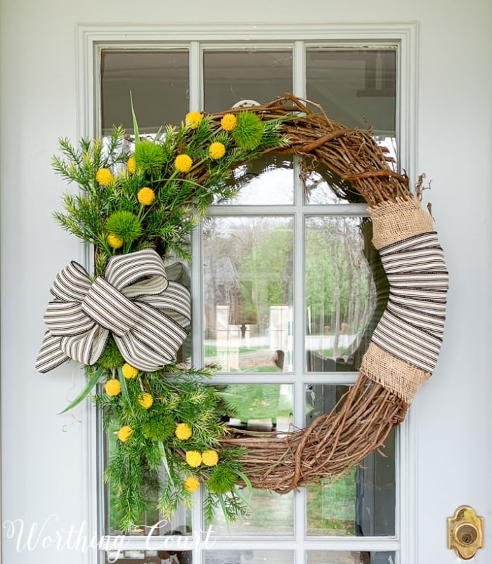 spring wreath hanging on a front door with glass