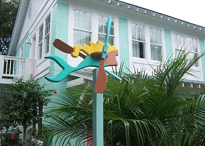 exterior view of house painted aqua with a mermaid whiligig in front