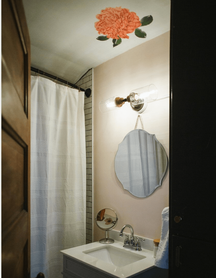 bathroom wall with round mirror, flower painted on the ceiling, pink flowers, white shower curtain 