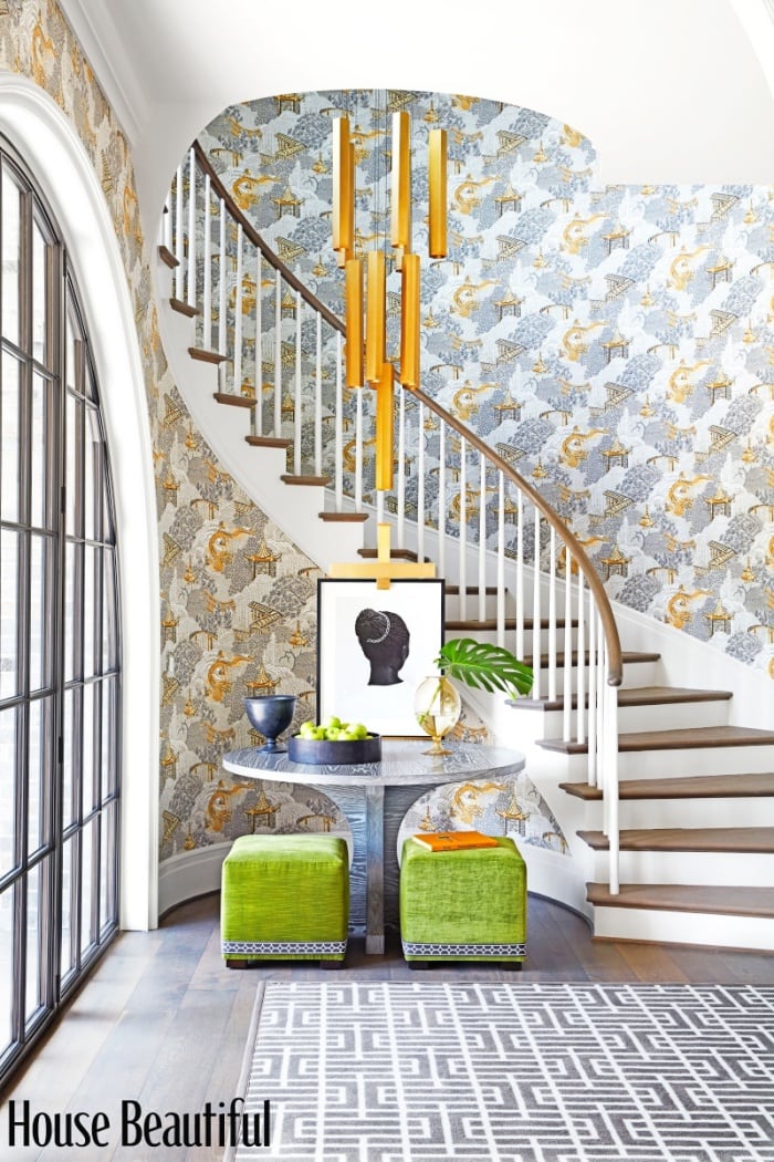 wallpapered foyer with curving staircase and modern furnishings