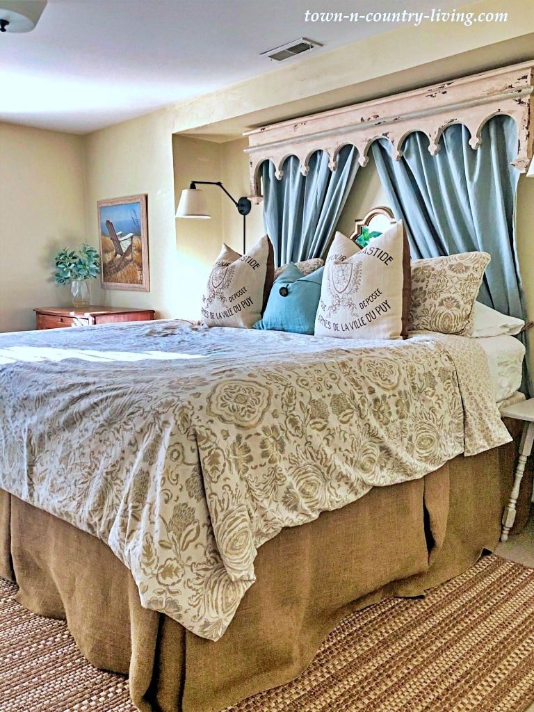 french country style bed with neutral bedding and a blue partial canopy