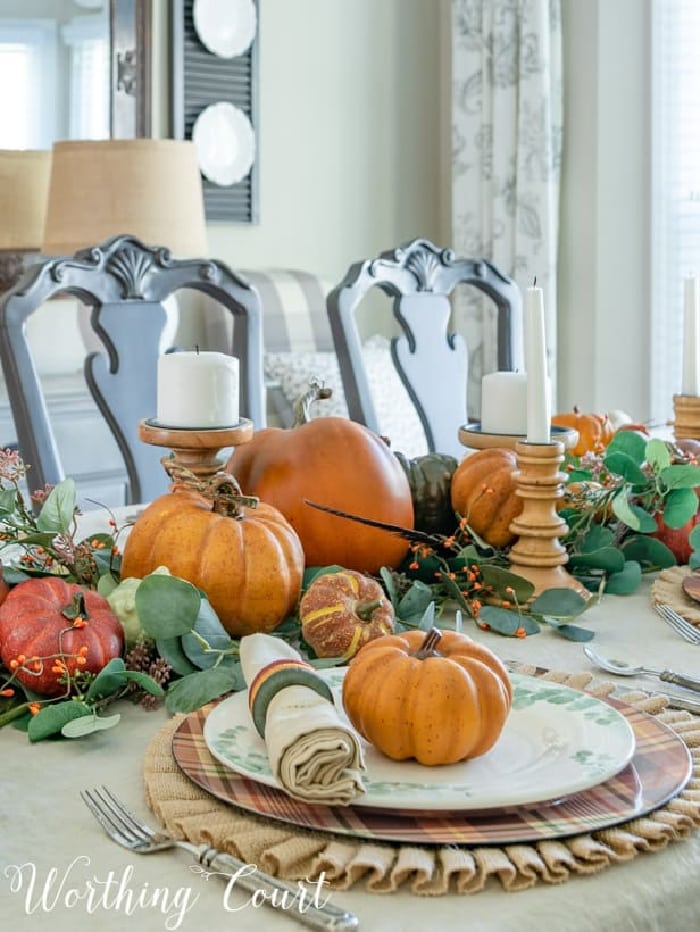 Thanksgiving table centerpiece made with orange pumpkins and green eucalyptus leaves