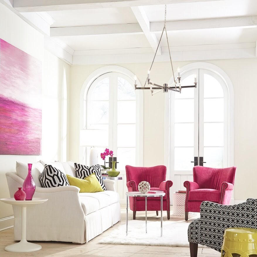 white living room with hot pink armchairs, black and white patterned pillows, lime yellow details in a large white room with floor windows