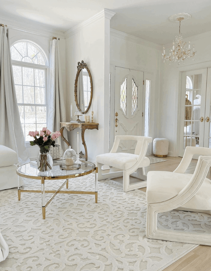 Entrance seating area featuring white couch and pink flowers and wite airmchairs of a Sophisticated Versailles Inspired Home Tour 