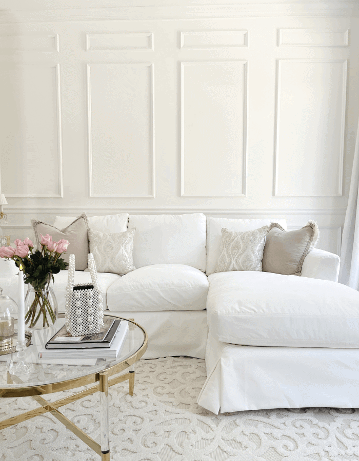Entrance seating area featuring white couch and pink flowers of a Sophisticated Versailles Inspired Home Tour 