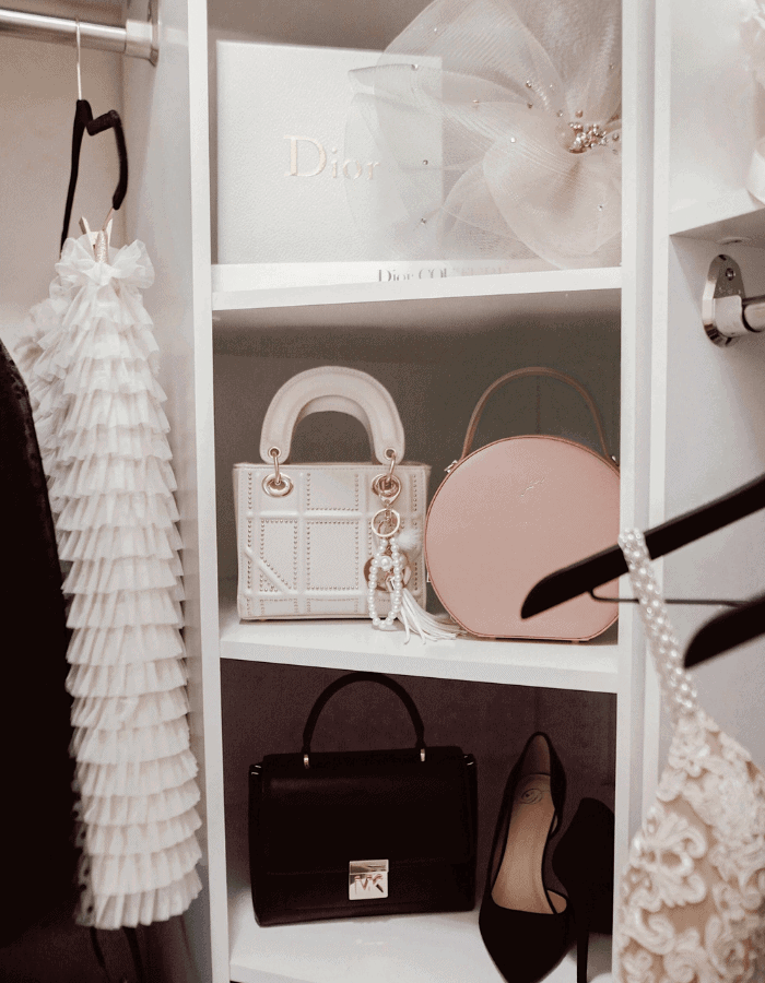 small closet in modern glam style with pink, black and white dresses and bags