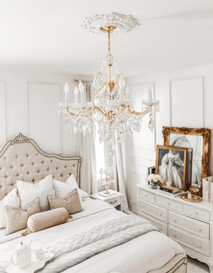 Versailles inspired bedroom featuring tufted bed and french framed paintings 