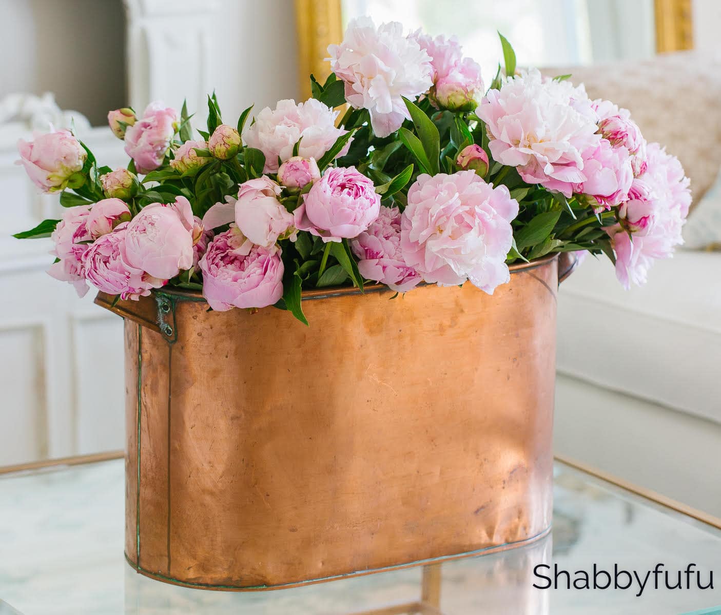 Example of how to clean tarnish from copper featuring a copper flower vase with pink peonies against a classy neutral living room