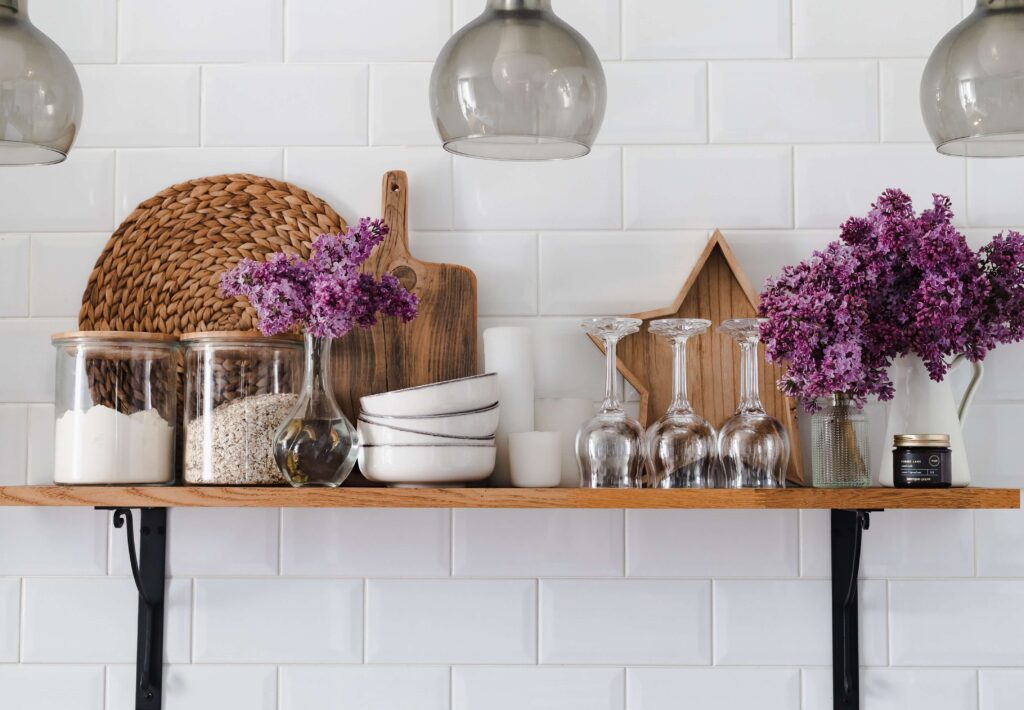 open kitchen shelf with white ceramic plates, whicker placemats and purple flowers, idea to prepare your home for spring