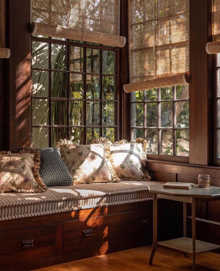 cozy daybed surranded by windows with draped bimboo shades