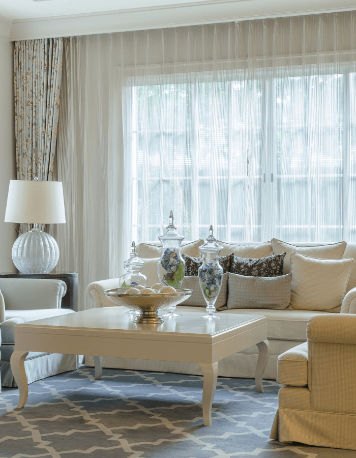 A living room with a large window featuring sheer curtains as the window treatments.