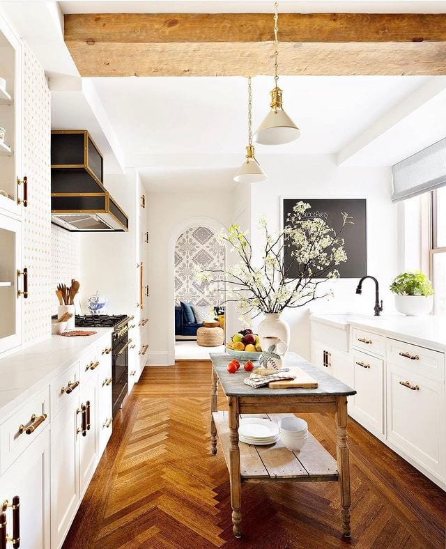 Kitchen design with scale and proportion applied, featuring wooden floors, white cabinets and rustic island table
