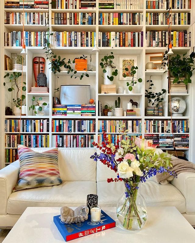 idea for when redecorating your home for free features a wall to wall bookshelf with books, plants and decorative elements
