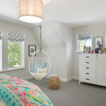 kids bedroom in coastal cottage home featuring a white bamboo hammock chair and floral bedding