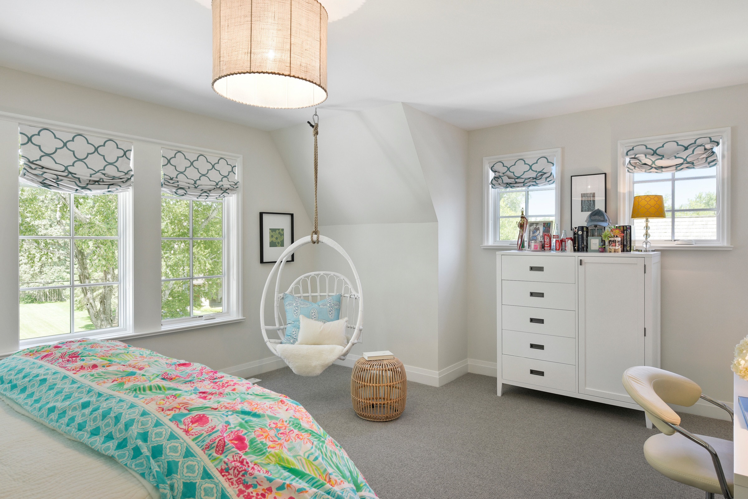 kids bedroom in coastal cottage home featuring a white bamboo hammock chair and floral bedding