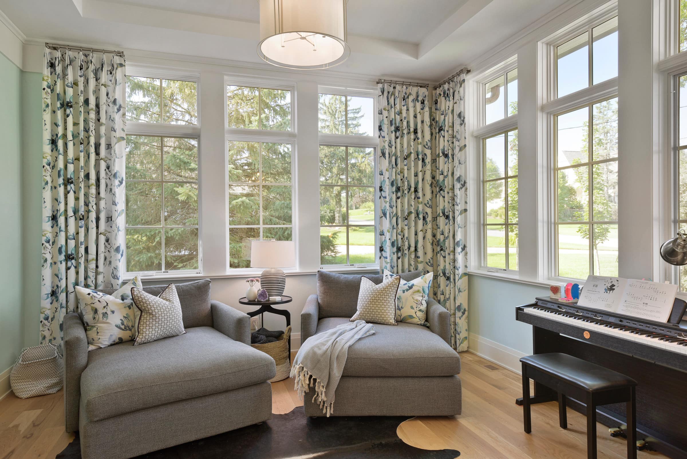family room featuring a piano and two armchairs in cottage coastal home