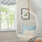 kids bedroom in coastal cottage home featuring a white bamboo hammock chair