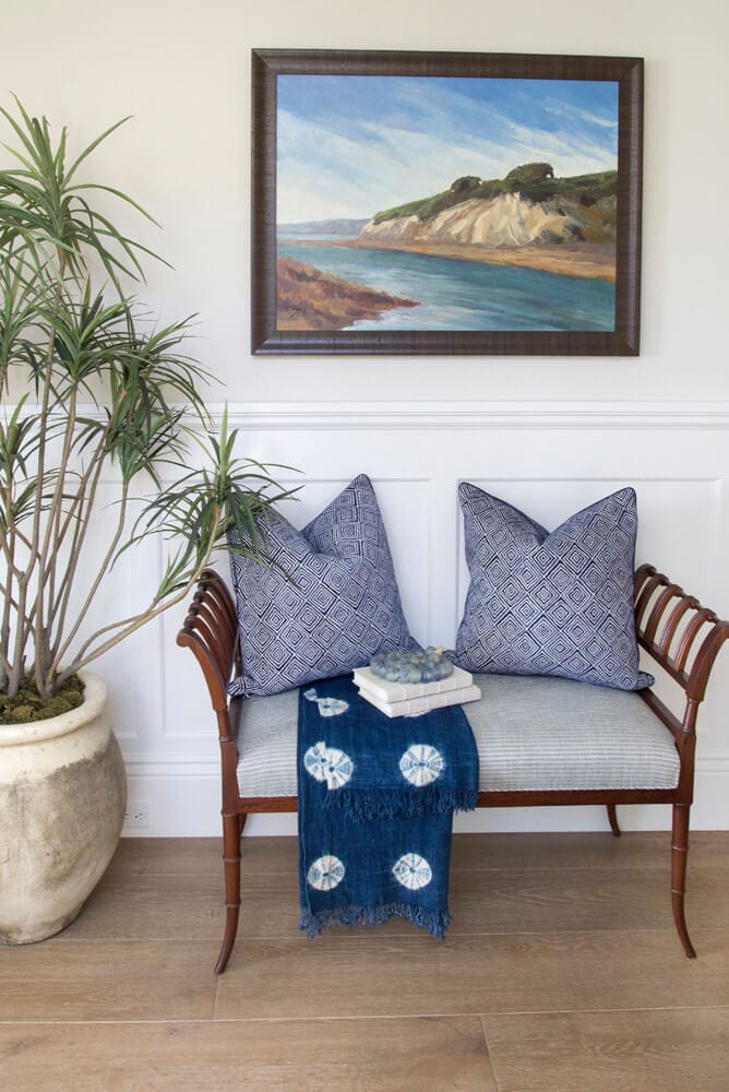 entryway in a cozy coastal home featuring blue pillows and a setee