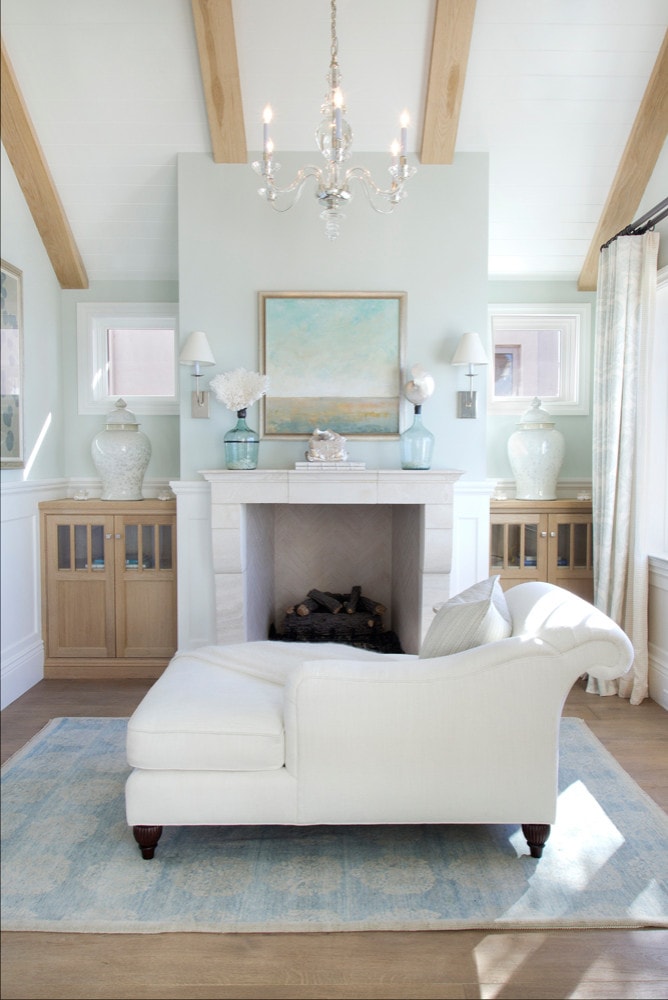 a chaise longue in a cozy coastal home facing a fireplace with coastal decor