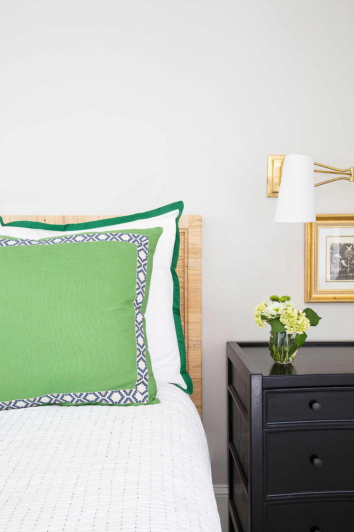 traditional bedroom featuring a rattan  headboard paired with green pillows