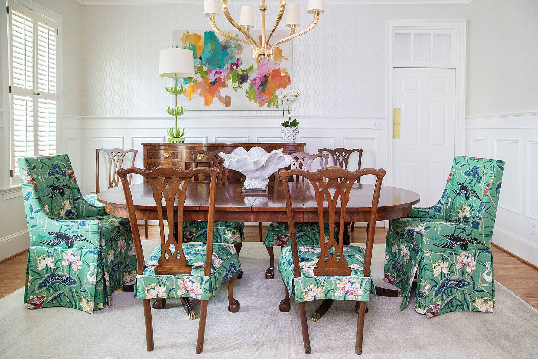 Traditional dining room featuring wood table and chairs with floral pattered covers in green and pink