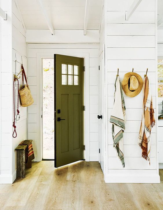 beach style entryway idea featuring hooks, small bench and a green front door