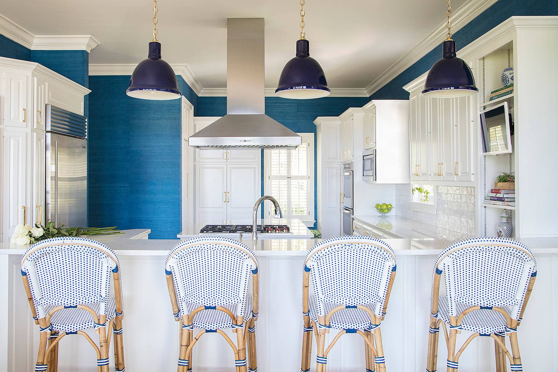 Home Tour: Kitchen featuring blue walls and white cabinets along with white and blue rattan chairs