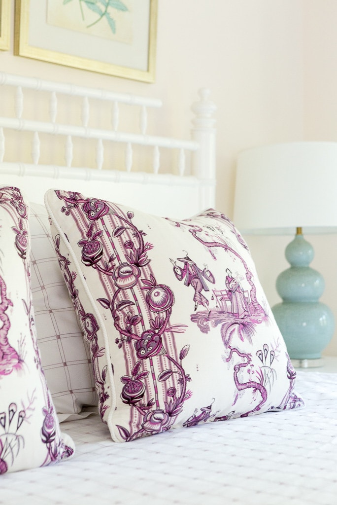 Bedroom in beach style home tour featuring a bed with pillows in purple and cream pattern