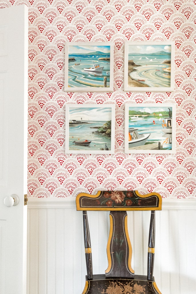Wall with white and red whimsical patterned wallpaper with framed paintings