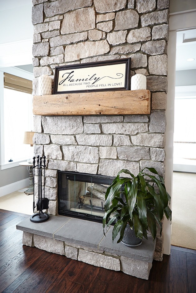 stone fireplace with a wood beam featured home tour