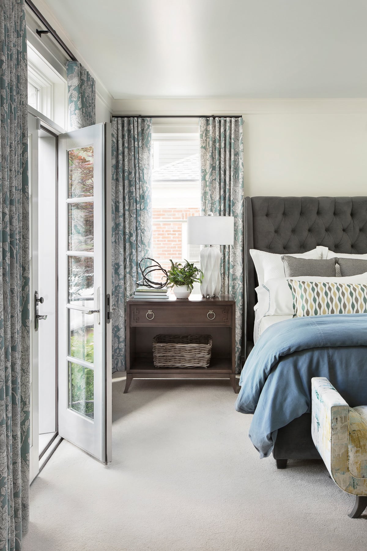 traditional bedroom featured in home tour showcasing a large bed with blue bedding and floral curtains