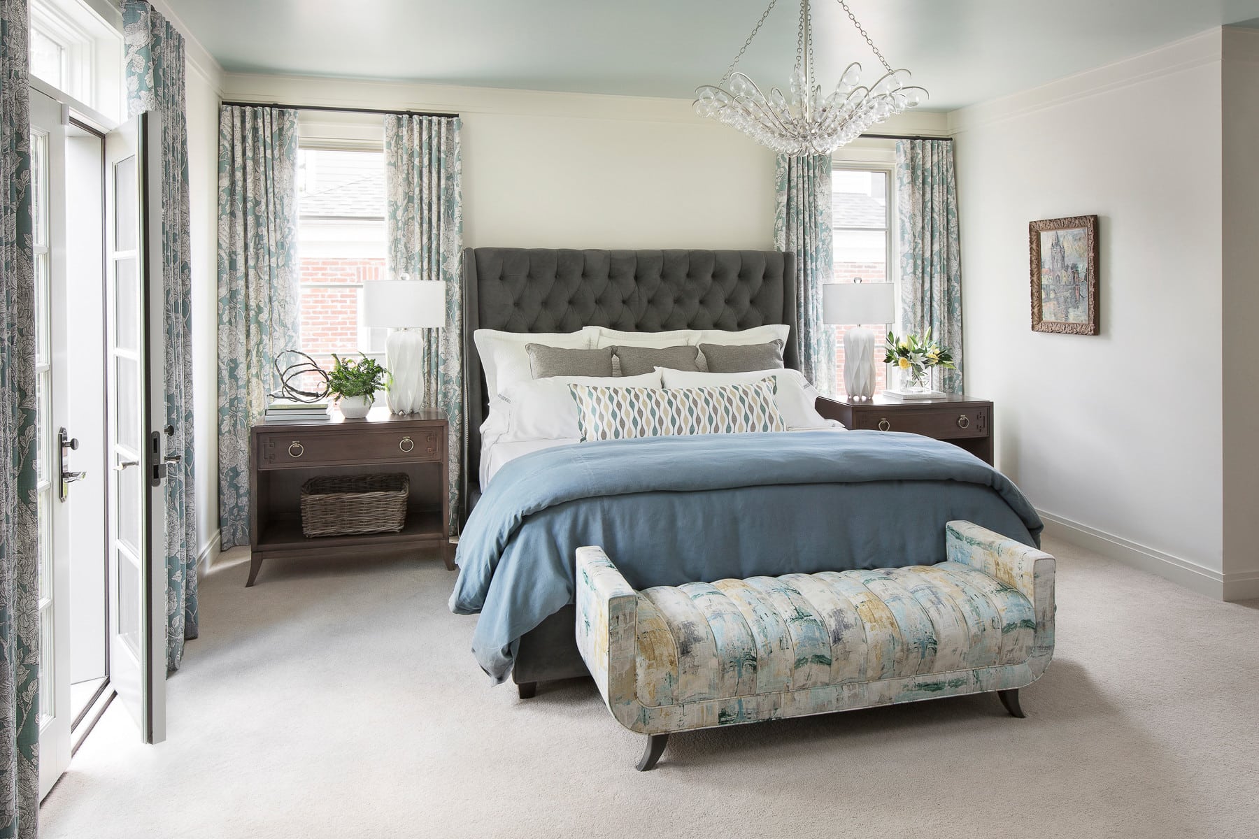 traditional bedroom featured in home tour showcasing a large bed with blue bedding and floral curtains