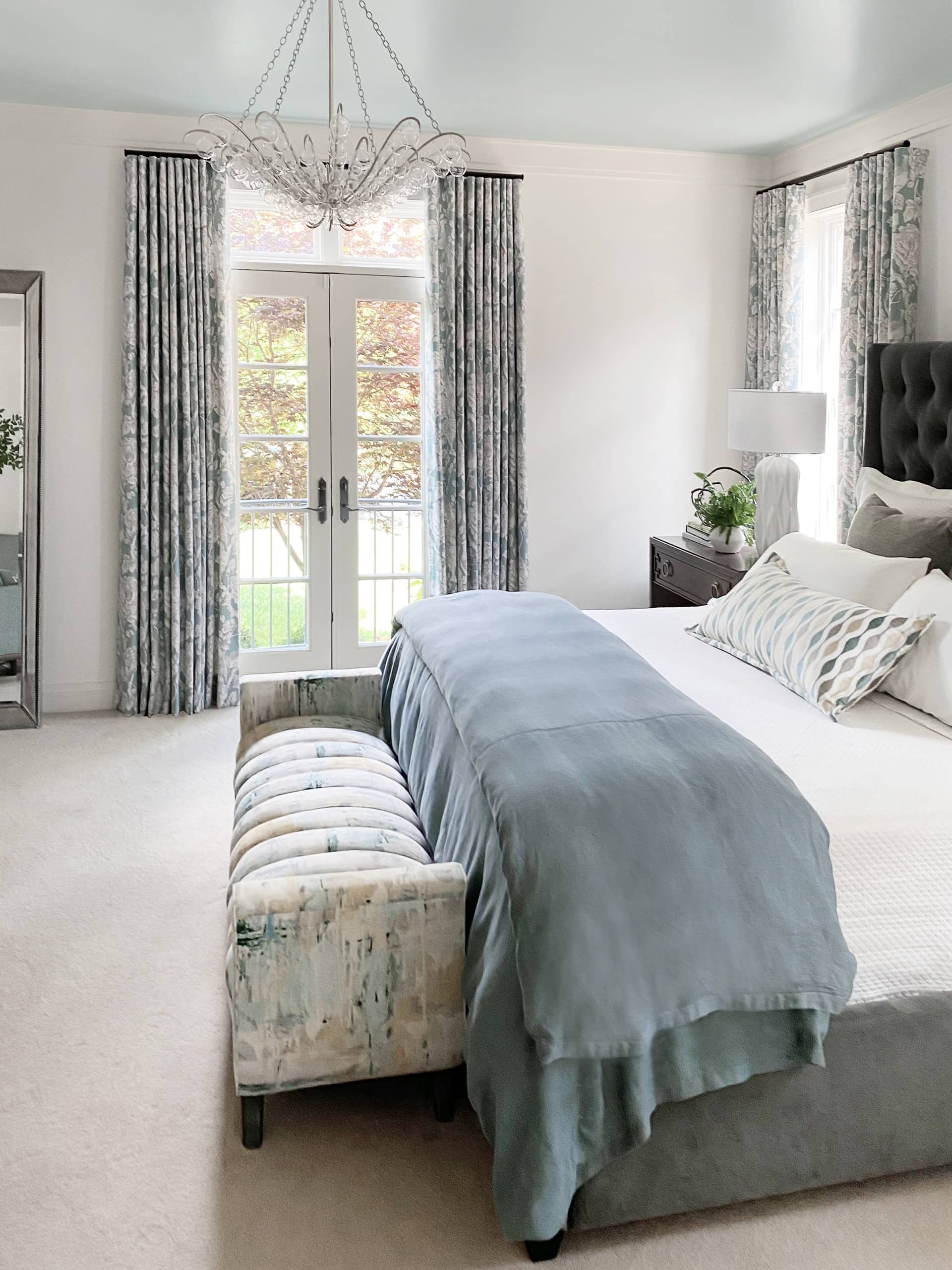 traditional bedroom featured in home tour showcasing a large bed with blue bedding and floral curtains