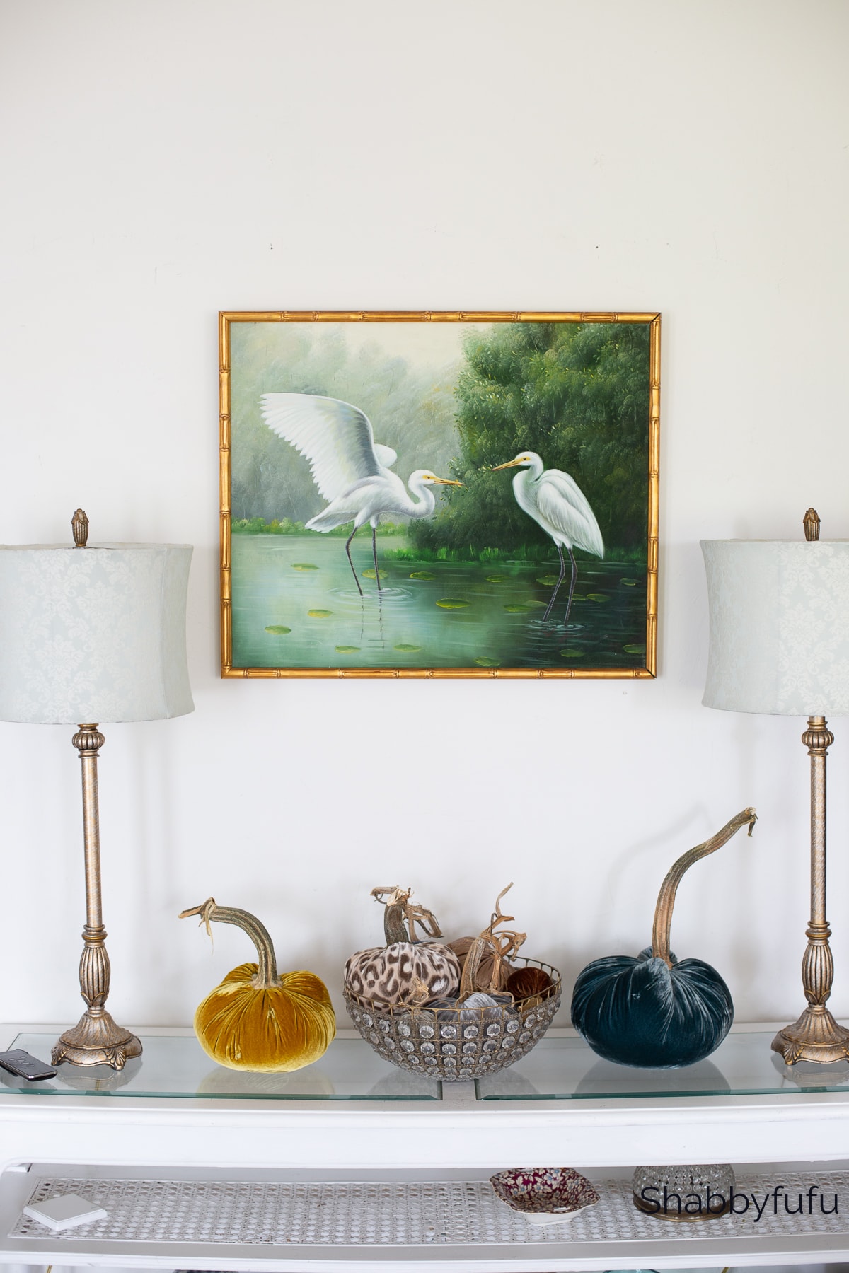 living room console table with a vintage tropical bird painting