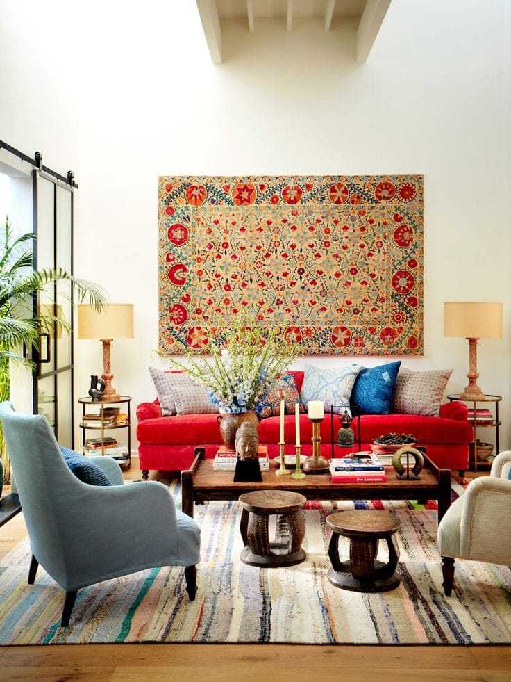 Mixing vintage and antiques in modern spaces idea featuring a modern living room with red sofa and framed vintage tapestry