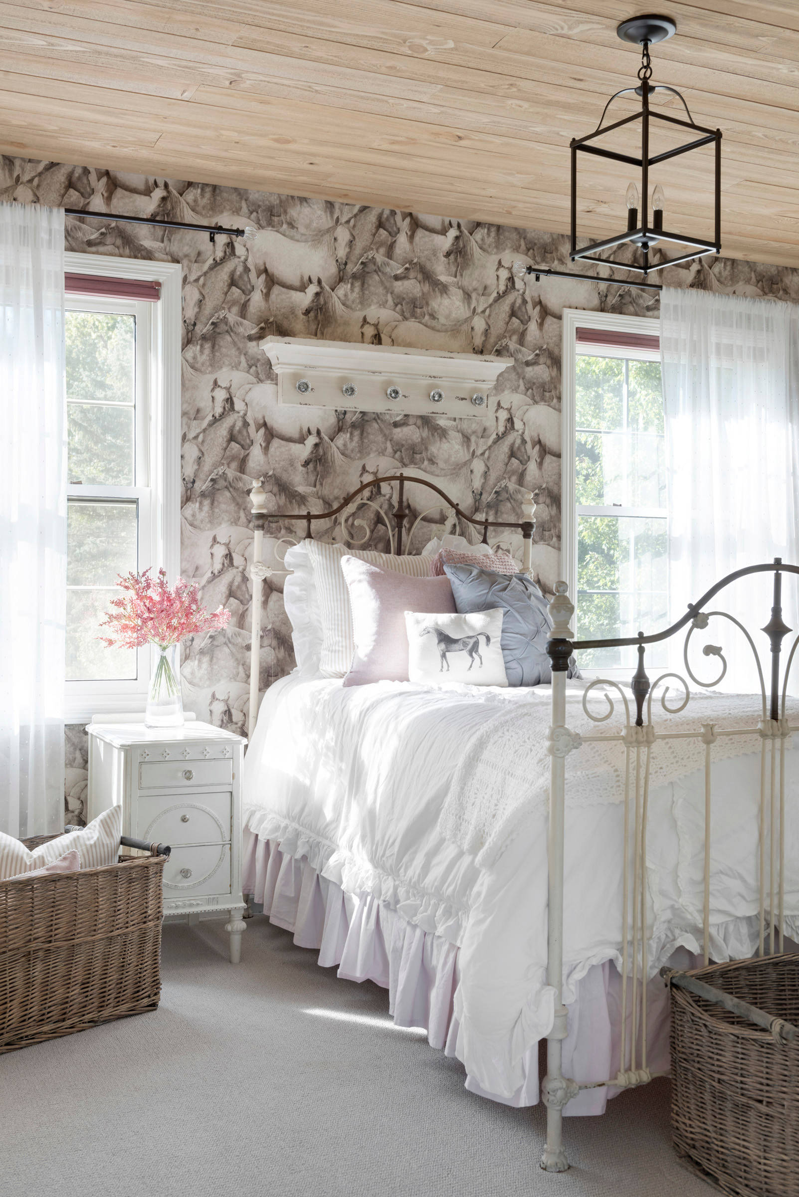 bedroom in farmhouse style featuring a vintage bedframe against a wallpaper of horses illustration featured in home tour