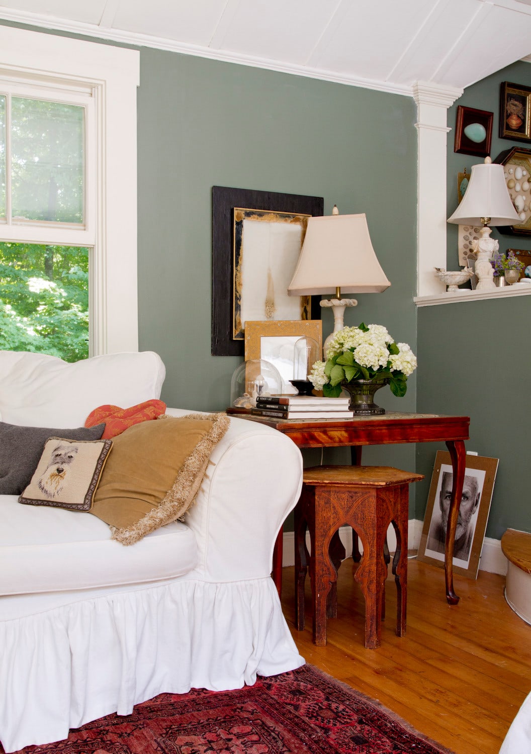 Whimsical and retro inspired style in a cottage living room featured in home tour. Green walls, white sofa next to side tables.
