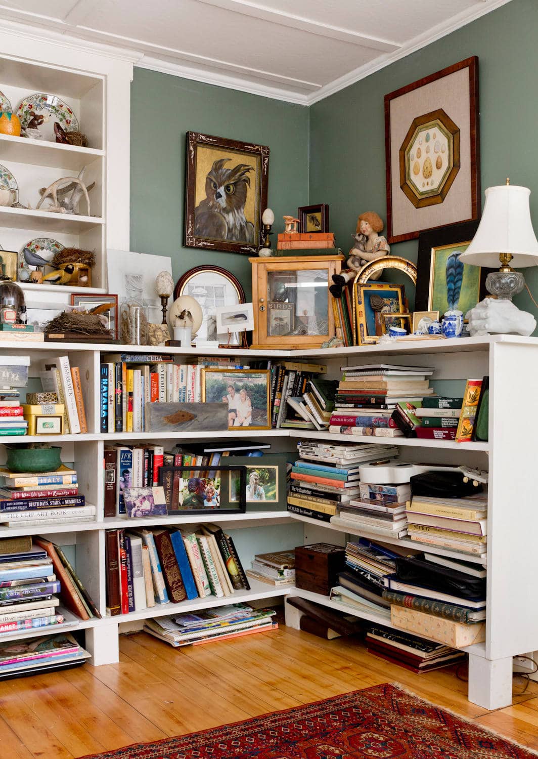 Cottage living room featured in home tour, showing a corner bookshelf with books and figurines.